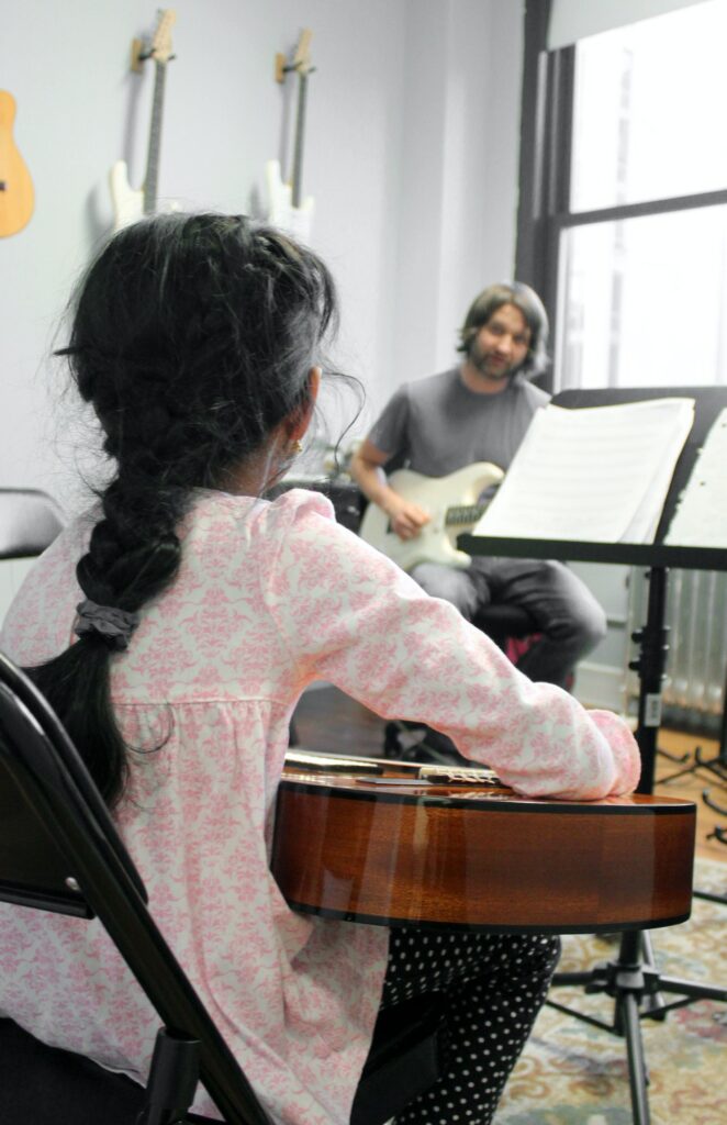 A Student Learning Music Lessons with a Guitar.